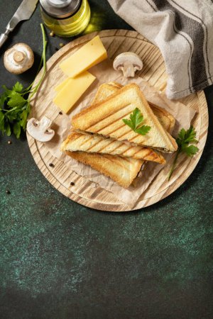 Photo for Delicious sandwich with grilled cheese, bacon and mushroom. Homemade breakfast on a dark stone tabletop. View from above. Copy space. - Royalty Free Image