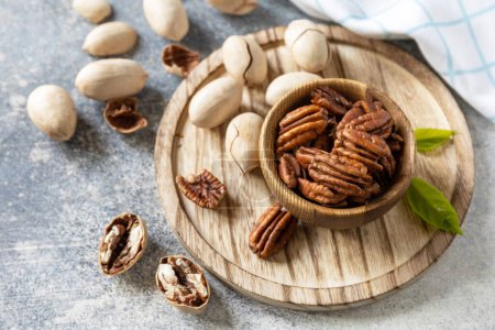 Photo for Nuts and seeds, healthy fats, various trace elements and vitamins. Bowl with pecan nuts on a stone table. Copy space. - Royalty Free Image