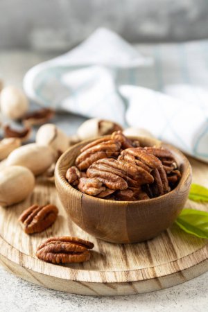 Photo for Nuts and seeds, healthy fats, various trace elements and vitamins. Bowl with pecan nuts on a stone table. Copy space. - Royalty Free Image