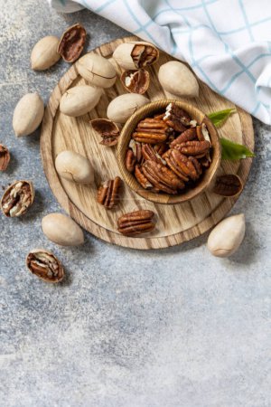 Photo for Bowl with pecan nuts on a stone table. Nuts and seeds, healthy fats, various trace elements and vitamins. View from above. Copy space. - Royalty Free Image