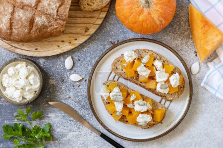 Photo for Healthy food, vegetarian appetizer. Open sandwiches whole grain bread with spice pumpkin and feta cheese on a stone table. View from above. - Royalty Free Image
