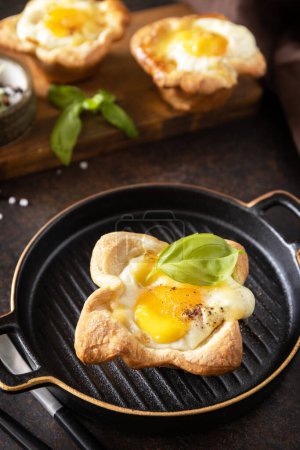 Téléchargez les photos : Œufs brouillés en pâte feuilletée avec fromage et bacon sur une assiette en pierre. Idée de petit déjeuner, snack food. - en image libre de droit