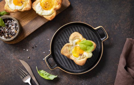 Téléchargez les photos : Idée de petit déjeuner. Œufs brouillés en pâte feuilletée avec fromage et bacon sur une assiette en pierre. Vue d'en haut. - en image libre de droit