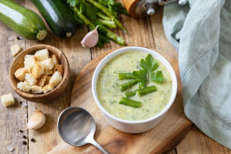 Foto de Puré de sopa vegana de verduras verdes. Dieta saludable baja en carbohidratos. Cuenco de frijol verde y sopa de crema de calabacín en una mesa rústica. - Imagen libre de derechos