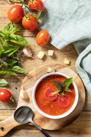 Téléchargez les photos : Bol de soupe à la crème de tomate avec basilic et croûtons sur une table rustique. Soupe végétalienne purée de tomates. Une alimentation saine faible en glucides. Vue d'en haut. - en image libre de droit
