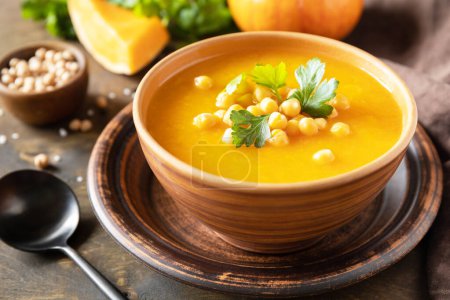 Photo for Vegetarian pumpkin and chickpea cream soup on a rustic wooden table. Comfort food, fall and winter healthy slow food concept. - Royalty Free Image