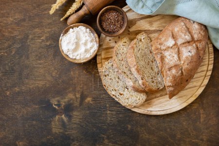 Photo for Bread from whole wheat grains, wheat bran, seeds, bio-ingredients over rustic table background. Homemade baking,  healthy lifestyle. View from above. Copy space. - Royalty Free Image