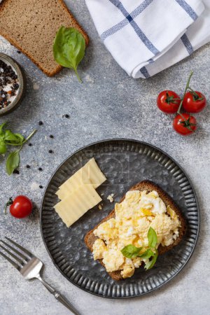 Photo for Homemade breakfast or brunch meal - scrambled eggs. Scrambled eggs on whole grain bread on a stone table. View from above. - Royalty Free Image