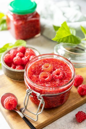 Photo for Delicious raspberries jam or jelly and fresh raspberries on a stone table. Homemade preservation. - Royalty Free Image