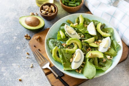 Photo for Organic green avocado and spinach salad with eggs, green beans, nuts on a stone table. Healthy food, summer healthy eating. Copy space. - Royalty Free Image