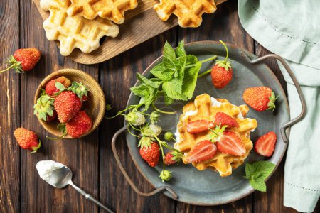 Foto de Gofres belgas caseros con fresas frescas berrie y queso ricotta para el desayuno en una mesa rústica. Vista desde arriba. - Imagen libre de derechos