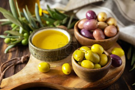 Téléchargez les photos : Des baies d'olives fraîchement cueillies dans des bols en bois et de l'huile pressée servie sur de vieilles planches en bois. - en image libre de droit