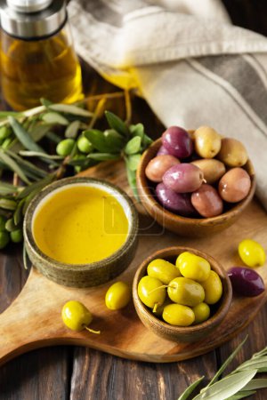 Photo for Freshly picked olives berries in wooden bowls and pressed oil served on old wooden boards. - Royalty Free Image