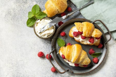 Photo for Healthy food dessert concept, french pastry. Tasty freshly baked croissants with cream cheese and raspberry on a stone background. View from above. Copy space. - Royalty Free Image