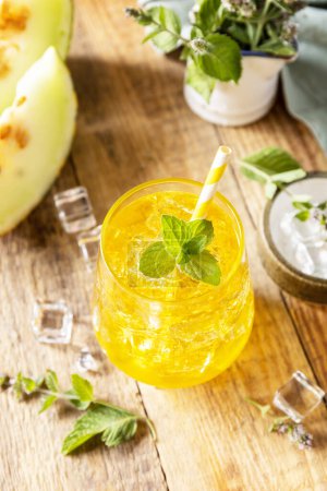 Photo for Melon lemonade in glasses with ice and mint on a wooden rustic table. Fresh refreshing fruity summer drink, seasonal beverages. - Royalty Free Image