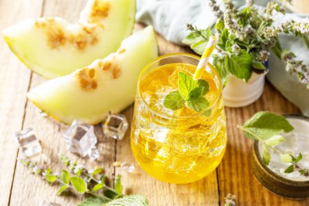 Photo for Fresh refreshing fruity summer drink, seasonal beverages. Melon lemonade in glasses with ice and mint on a wooden rustic table. - Royalty Free Image