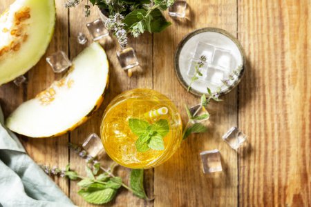 Photo for Melon lemonade in glasses with ice and mint on a wooden rustic table. Fresh refreshing fruity summer drink, seasonal beverages. View from above. Copy space. - Royalty Free Image