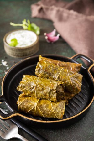 Photo for Delicious dolma - stuffed grape leaves with rice and meat on a dark stone background. Traditional Greek, Caucasian and Turkish cuisine. - Royalty Free Image