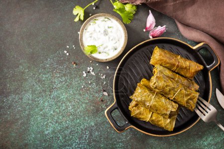 Photo for Delicious dolma - stuffed grape leaves with rice and meat on a dark stone background. Traditional Greek, Caucasian and Turkish cuisine. View from above. Copy space. - Royalty Free Image