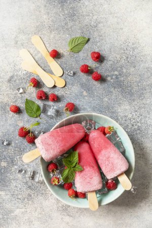 Téléchargez les photos : De la glace. Dessert d'été. Popsicles de framboises maison avec yaourt et framboises sur un fond de pierre grise. Vue d'en haut. - en image libre de droit