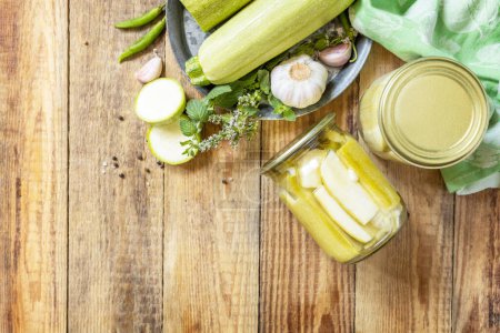 Photo for Healthy homemade fermented food. Pickled zucchini with mint preserved canned in glass jar. Home economics, autumn harvest preservation. View from above. Copy space. - Royalty Free Image