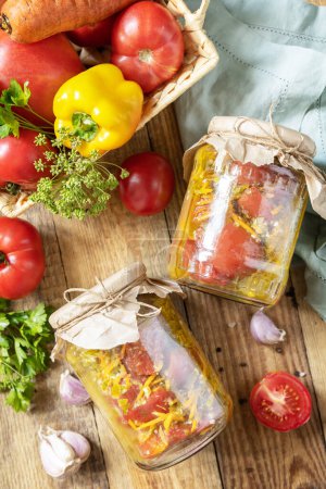 Photo for Healthy homemade fermented food. Salad tomatoes with vegetables on a rustic table. Home economics, autumn harvest preservation. View from above. - Royalty Free Image