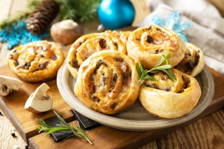 Photo for Pizza rolls puff pastry stuffed with prosciutto bacon, mushrooms and cheese on the Christmas table, italian appetizers. - Royalty Free Image