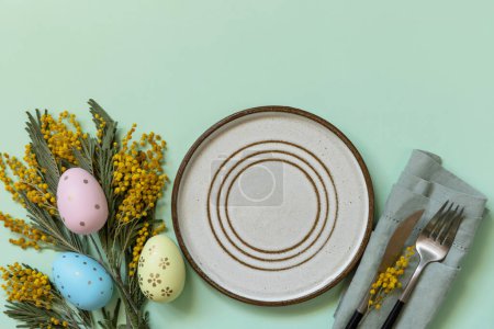 Téléchargez les photos : Table pour le dîner de Pâques avec œufs de Pâques et mimosa sur fond pastel. Décorations de Pâques concept. Vue d'en haut. Espace de copie. - en image libre de droit