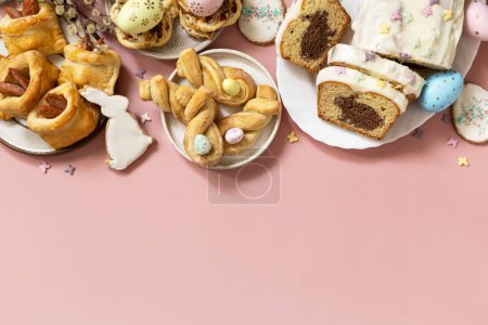 Téléchargez les photos : Joyeuses pâtisseries et cupcakes de Pâques avec lapin de Pâques sur fond rose pastel. Petit déjeuner de Pâques ou brunch sur une table de fête. Vue d'en haut. Espace de copie. - en image libre de droit