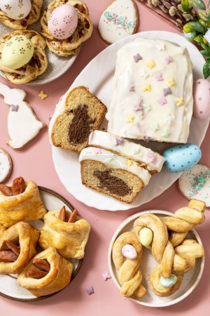 Téléchargez les photos : Joyeuses pâtisseries et cupcakes de Pâques avec lapin de Pâques sur fond rose pastel. Petit déjeuner de Pâques ou brunch sur une table de fête. Vue d'en haut. - en image libre de droit