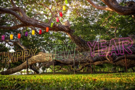 Foto de Happy New Year decorative light on the big tree in the green public garden at the side of the sea in the morning rise - Imagen libre de derechos