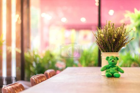 Foto de Oso de peluche verde en la parte superior de la mesa de madera en la cafetería por la mañana, café o café fondo - Imagen libre de derechos