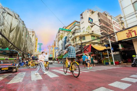 Foto de BANGKOK, TAILANDIA - 22 de abril de 2023, El viajero monta la bicicleta para ver la vida de la ciudad por la mañana en el Barrio Chino de Bangkok o Yaowarat Road, la famosa calle comercial emblemática de Tailandia. - Imagen libre de derechos