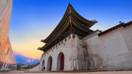 Téléchargez les photos : Surplombant un magnifique coucher de soleil, la porte de Gwanghwamun sert d'entrée principale au palais Gyeongbokgung et est la plus grande des portes situées sur son côté sud.. - en image libre de droit