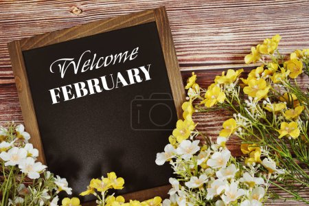 Mensaje de texto de bienvenida de febrero con decoración de flores sobre fondo de madera