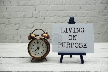 Téléchargez les photos : Living on Purpose texte et réveil sur mur de briques blanches et fond en bois - en image libre de droit