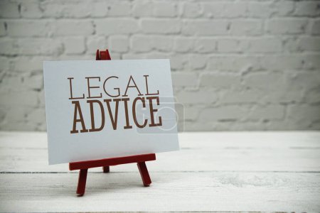 Photo for Legal Advice text on white brick wall and wooden background - Royalty Free Image