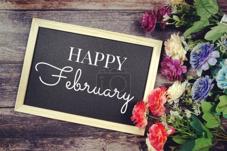 Feliz febrero tipografía texto y decoración de flores sobre fondo pizarra
