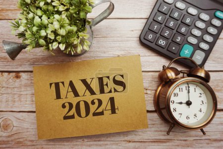 Téléchargez les photos : Taxes 2024 typographie texte avec calculatrice sur fond bois - en image libre de droit