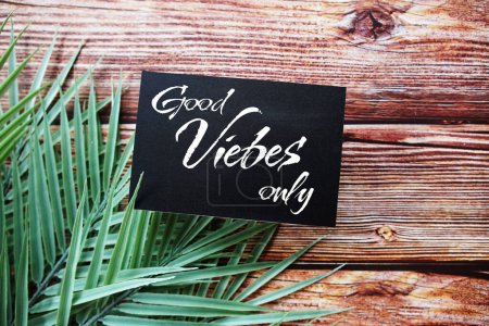 Téléchargez les photos : Bonnes vibrations seulement message texte vue du dessus sur fond en bois avec décoration de feuilles vertes - en image libre de droit
