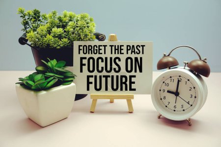 Photo for "Forget The Past Focus on Future" Inspirational and motivational quote written on paper card with alarm clock on blue background - Royalty Free Image