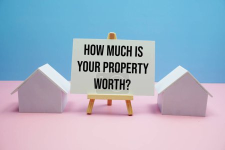 Téléchargez les photos : Combien vaut votre propriété ? message texte avec modèle de maison sur fond bleu et rose, Concept de logement Immobilier - en image libre de droit