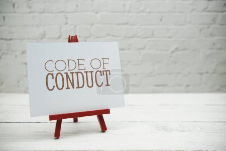 Foto de Código de conducta texto sobre pared de ladrillo blanco y fondo de madera - Imagen libre de derechos
