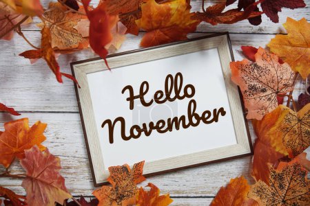 Hello November text message top view with maple leaf decoration on wooden background