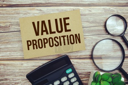Value Proposition text message with calculator and magnifying top view on wooden background