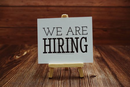 We are Hiring text on paper card on wooden background