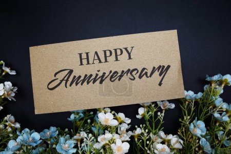Photo for Happy Anniversary text message with flower decoration on black background - Royalty Free Image