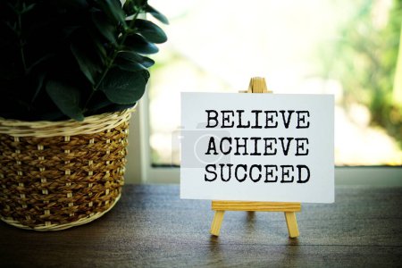 Photo for Believe Achieve Succeed text message on paper card with wooden easel on wooden table background, inspiration motivation concept - Royalty Free Image
