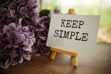Photo for Keep simple text message text message on paper card with wooden easel on wooden table background, inspiration motivation concept - Royalty Free Image
