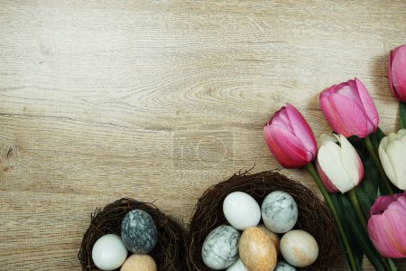 Easter background with eggs and flowers bouquet top view on wooden background